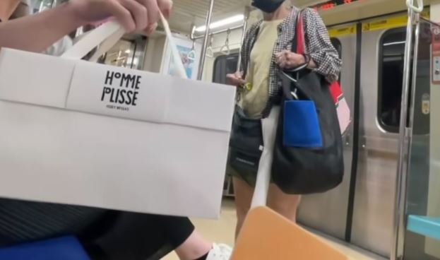 遭逼讓座的乘客請旁人幫拿 HOMME PLISSÉ ISSEY MIYAKE 提袋